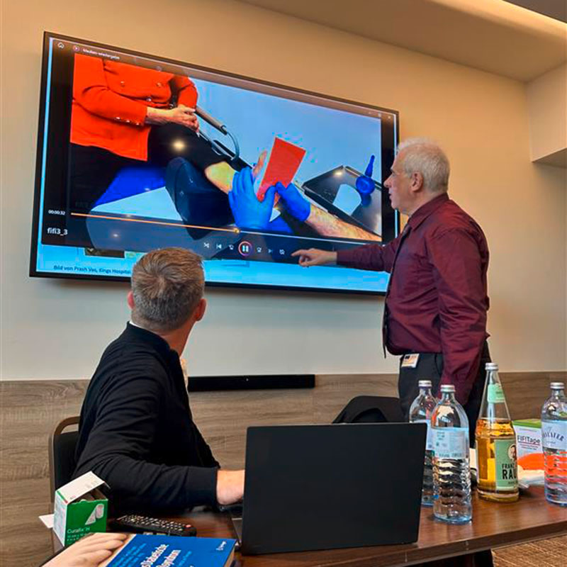 Vortragender zeigt auf TV zum Thema Wundversorgung